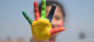 A kid showing colored fingers.