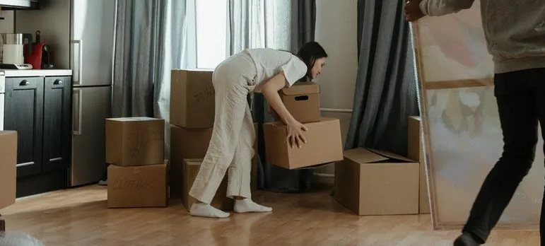 A woman moving cardboard boxes