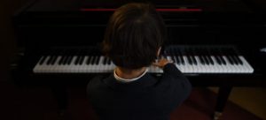 child playing a piano in a music school