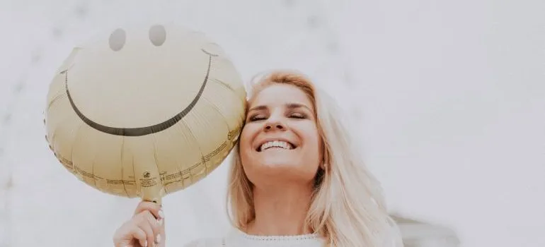 A woman holding a smiley balloon