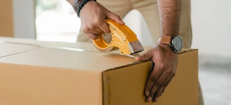 a man taping the box - negotiate with movers