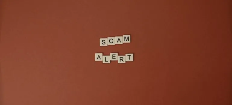 the word scam alert as letters from scrabble to represent a hired fraudulent mover