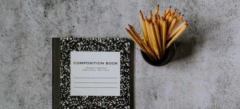  A notebook on the desk with a bowl of pencils as a reminder to first write down a plan for how to pack mirrors for relocation 