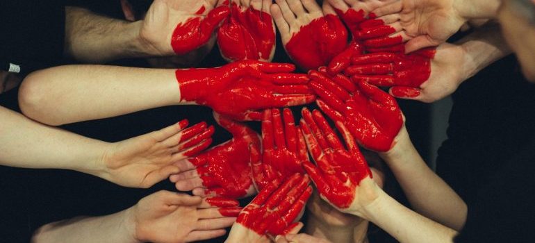 A few human hands colored in red, formating a heart 