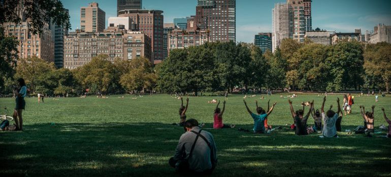 People exercising and sitting on the meadow in Central Park on a sunny day