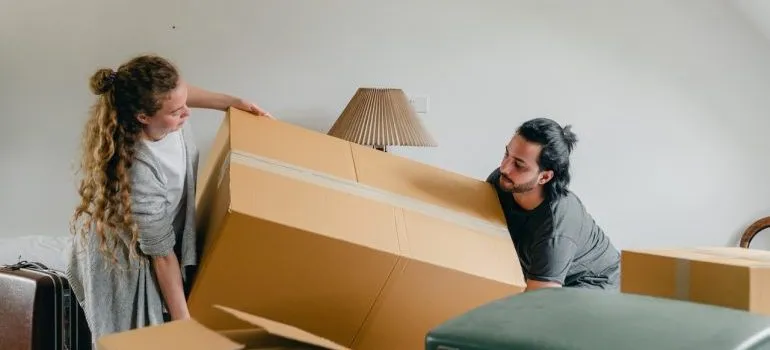 a man and woman carrying a large box