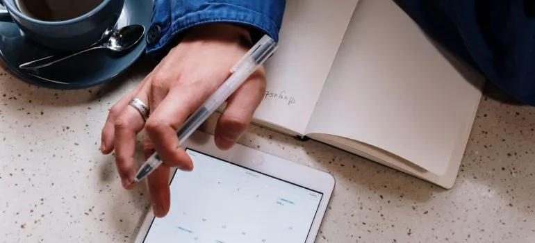 A man holding a pen and typing on a tablet.
