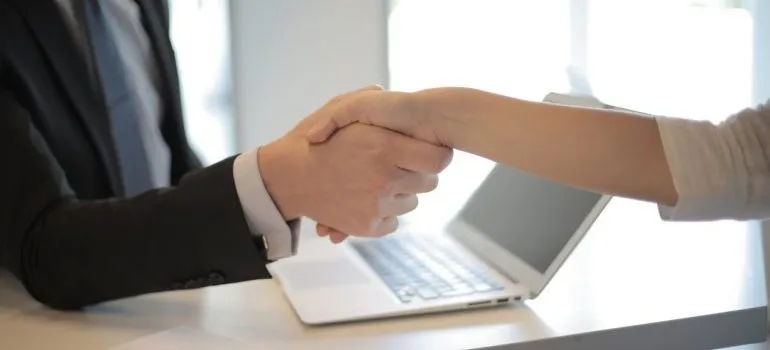 Person shaking hands after hiring movers before moving their piano across Manhattan
