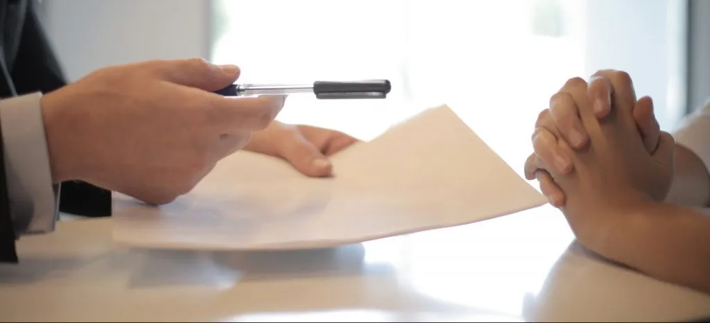 a man handing over a pencil to a woman