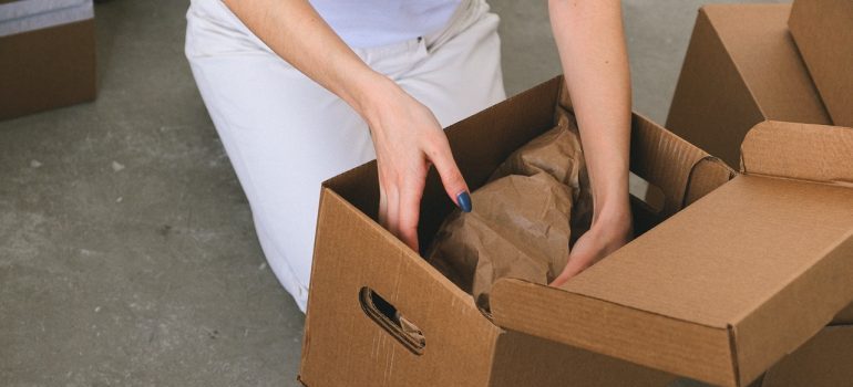 A woman packing her belognings into a cardboard box