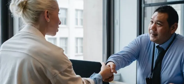 Woman shaking hands after hiring movers to avoid property damage when relocating to Manhattan
