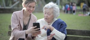 a woman showing something to her mother on the phone as something you should do to adequately prepare for moving your elderly parents across state