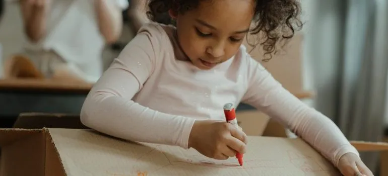 A girl writing on a moving box