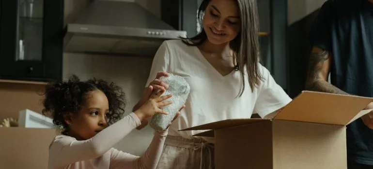 a little girl handing a wrapped item to her mother for packing