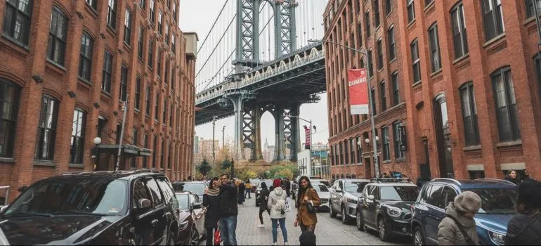 people walking through the street with the Brooklyn Bridge behind them