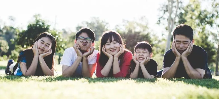 a family of five lying on the grass havin fun at a picnic as a part of moving a large family from Bronx to NJ