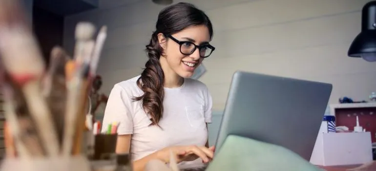 Young woman using a laptop and reading the moving guide for international art collectors