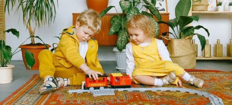 two toddlers sitting on the floor while playing with their toys