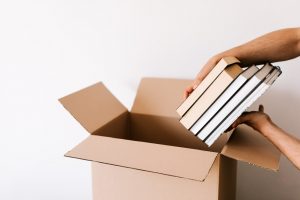 A person thinking about packing advice for minimalist while packing selected books