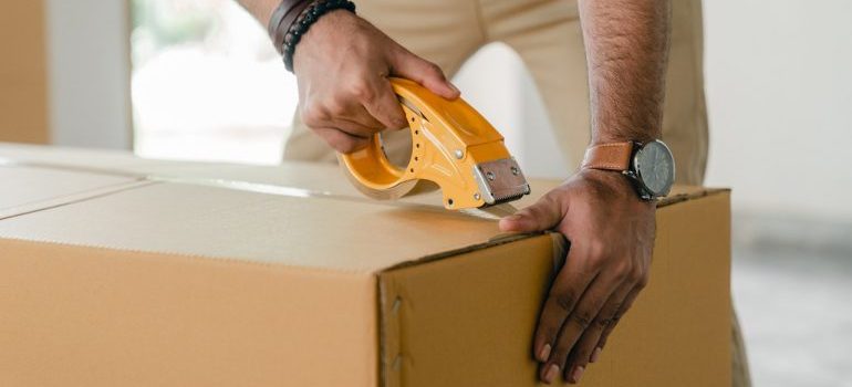 Man taping a cardboard box with scotch tape